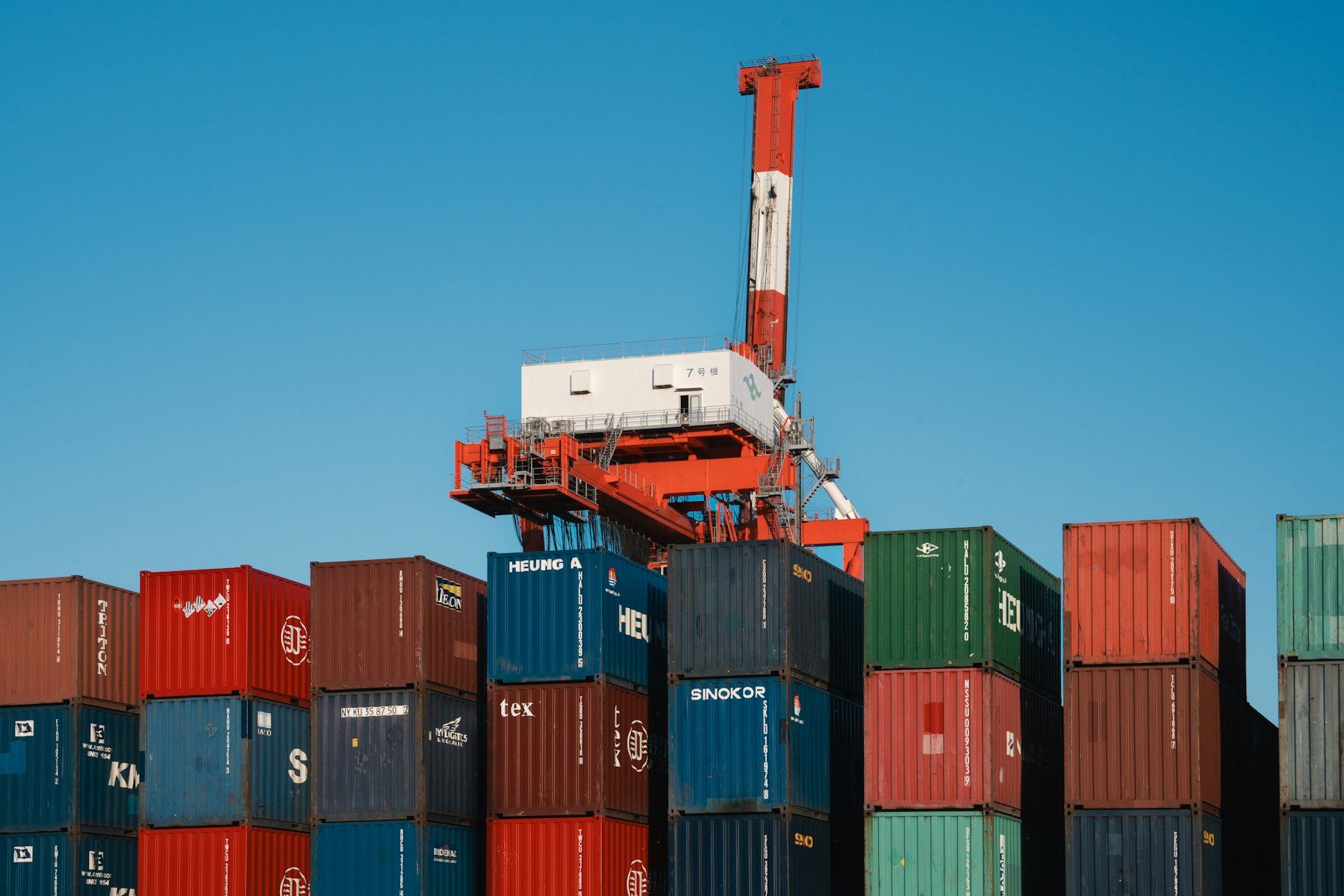 Portique rouge et blanc au-dessus de conteneurs empilés dans un port